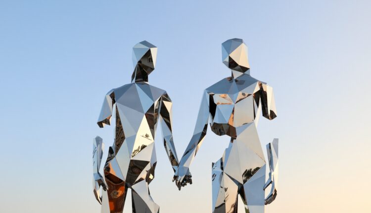 Two geometric human figures holding hands and looking at each other. Composed out of mirror material.